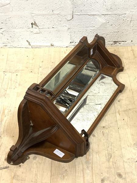 An Edwardian walnut corner wall bracket, with sectional bevelled mirror plates over an open shelf