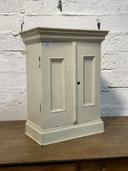A 19th century white painted hardwood wall hanging medicine cabinet, with two doors enclosing two