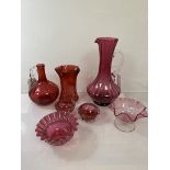 A collection of cranberry glass including a footed jug of spiral tulip form (28cm), a further jug, a