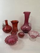 A collection of cranberry glass including a footed jug of spiral tulip form (28cm), a further jug, a