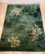 A Chinese washed wool carpet, the green field with floral motifs, 350cm x 247cm