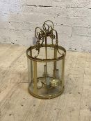 A cylindrical brass and glass four branch hanging lantern with chain and ceiling rose, H64cm D35cm