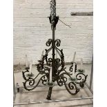 An early 20th century French patinated wrought metal chandelier, the hammered copper boss in the