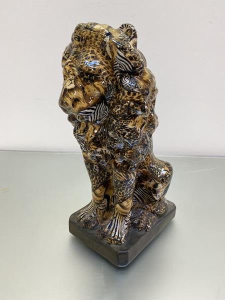 An upright china figure of a Male Seated Lion figure, decorated with collage zebra, cheetah etcc.,