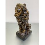An upright china figure of a Male Seated Lion figure, decorated with collage zebra, cheetah etcc.,