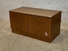 A mid century teak low cabinet with two doors enclosing a shelf, raised on a plinth base, H199cm,