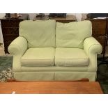 A two seater sofa with scrolled arms in herringbone mint green upholstery, 80cm x 138cm x 97cm