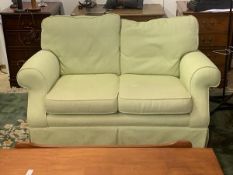 A two seater sofa with scrolled arms in herringbone mint green upholstery, 80cm x 138cm x 97cm