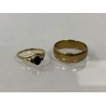 A 9ct gold wedding band, size U, and a 9ct gold gem set ring with centre blue stone flanked by