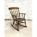 An early 20th century farmhouse rocking chair, the shaped crest rail over turned spindle back and