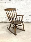 An early 20th century farmhouse rocking chair, the shaped crest rail over turned spindle back and