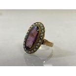 A 19thc dress ring with oval amethyst surrounded by seed pearls, possible later shank, markings