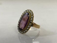 A 19thc dress ring with oval amethyst surrounded by seed pearls, possible later shank, markings