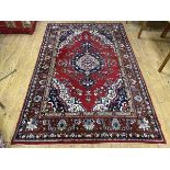 A North West Persian rug the central medallion within red field with foliate design, spandrels to