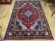 A North West Persian rug the central medallion within red field with foliate design, spandrels to