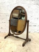 A Victorian mahogany vanity swing mirror, the oval mirror raised on moulded and scrolled supports