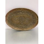 A large Syrian brass oval scalloped tray, the centre panel with stylised winged God and Syrian style