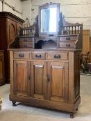 An early 20th century stained pine buffet, the top with swing mirror and four trinket drawer, over