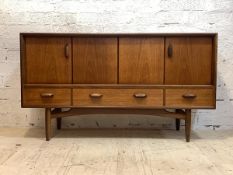 G-Plan, a mid century teak sideboard, with two folding doors each enclosing a shelf, over three