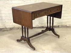 A Regency style walnut and mahogany sofa table, the cross banded and stung top with two drop