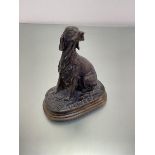 A cast bronze metal figure of a Red Setter seated on his haunches, on naturalistic style oval