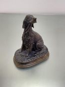 A cast bronze metal figure of a Red Setter seated on his haunches, on naturalistic style oval