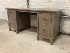 A contemporary stained pine desk, the rectangular top over two drawers and a cupboard, raised on