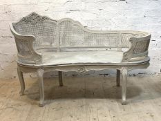 A white painted hardwood boudoir chaise in the Belle Epoche taste, with floral carved crest rail and