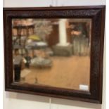 An Arts & Crafts Edwardian oak well carved relief framed wall mirror with bead and leaf scrolling