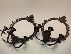 A pair of 19thc style cast iron circular framed wall mirrors with mask and c scroll surmounts fitted