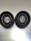 A pair of Edwardian ebonised oval frames containing painted silk panels depicting Regency female