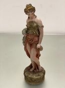 A Royal Dux style figure standing in naturalistic moulded circular base with gilt and polychrome