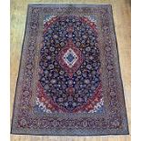 A Persian Kashan carpet, hand knotted, the deep blue field with blue red and ivory lozenge