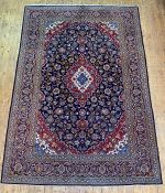 A Persian Kashan carpet, hand knotted, the deep blue field with blue red and ivory lozenge