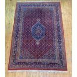 A Persian Heriz design carpet, hand knotted, the red field with lozenge medallion, multiple lotus