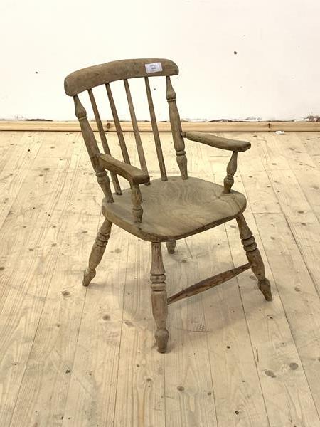A 19th century bleached elm and fruit wood childs armchair, with shaped crest rail, spindle back,