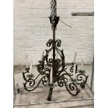An early 20th century French patinated wrought iron chandelier, the hammered copper boss in the form
