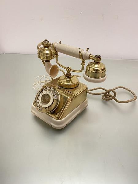 A Danish ivory coloured plastic and brass mounted circular dial telephone complete with BT