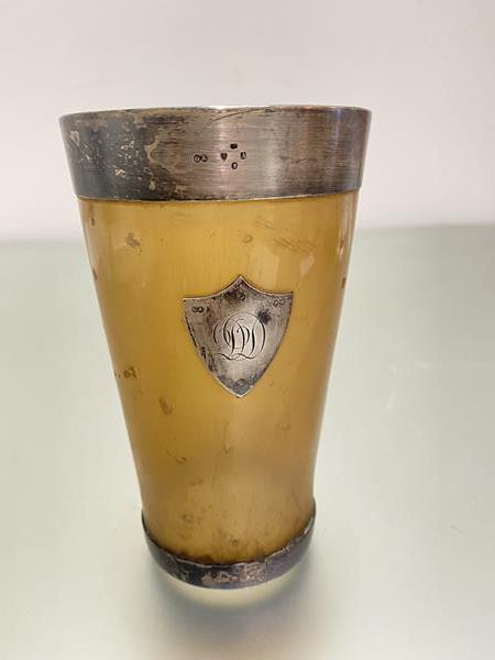 A George Adams silver mounted cow horn beaker with engraved crest and silver mount to glazed base,
