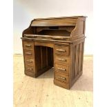 An early 20th century American oak tambour desk, the serpentine roll top (A/F) enclosing fitted