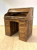 An early 20th century American oak tambour desk, the serpentine roll top (A/F) enclosing fitted