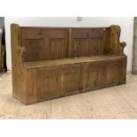 A 20th century reclaimed pine settle or hall seat, with shaped panel ends, four panel back over