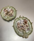 A pair of continental porcelain oval relief cast panels depicting winged cherubs with busts, in