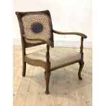 A 1930's stained beech library chair, the cane back with anthemion motif over upholstered seat and