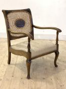 A 1930's stained beech library chair, the cane back with anthemion motif over upholstered seat and