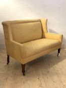 An Edwardian settee in the George III taste, the high wing back over out swept arms, upholstered