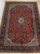 A Fine Persian Kashan hand knotted carpet, with floral medallion on a busy red field, enclosed by