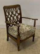 An early 20th century stained beech open armchair, with an unusual fret carved back panel over squab
