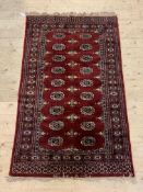 A hand knotted bokhara rug, the red field with two rows of guls and bordered, 96cm x 162cm