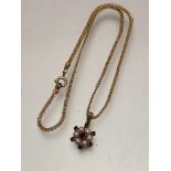 A 9ct gold garnet and seed pearl cluster pendant on yellow metal trace link chain, (pendant